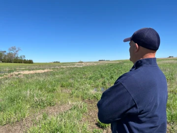 Mark Mueller looks over a field he’s set aside to return to native wetland in order to better conserve and filter water. The fourth generation farmer in Bremer County, Iowa, is dealing with dry conditions for a third year.