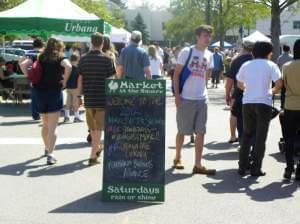 People walking amid food stalls at the Urbana Farmers Market
