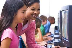 Teacher and student smiling as they look at a computer