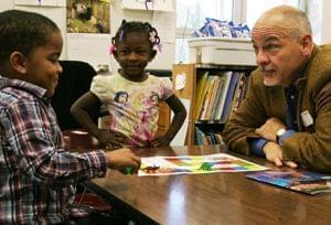 Book mentor Joe Murphy plays an educational dinosaur game with children.