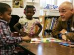 Book mentor Joe Murphy plays an educational dinosaur game with children.