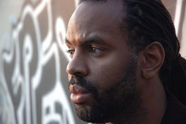 Byron Hurt standing in front of wall covered by grafitti
