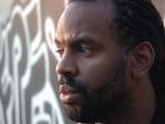 Byron Hurt standing in front of wall covered by grafitti