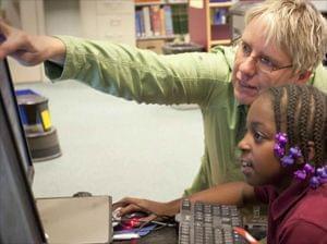 Kimberlie Kranich helping student edit video at computer.