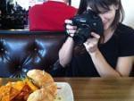 A young woman taking a photo of food at a restaurant.