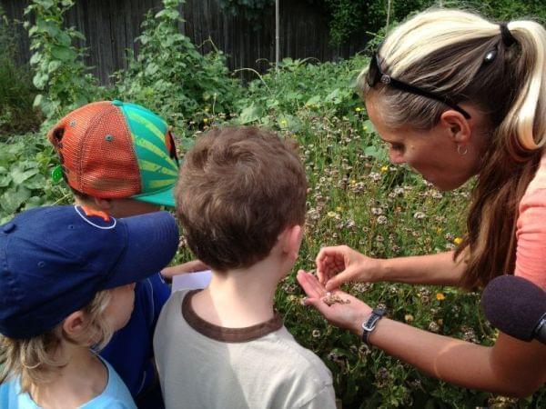 Woman showing a group of small children seeds in her hand.