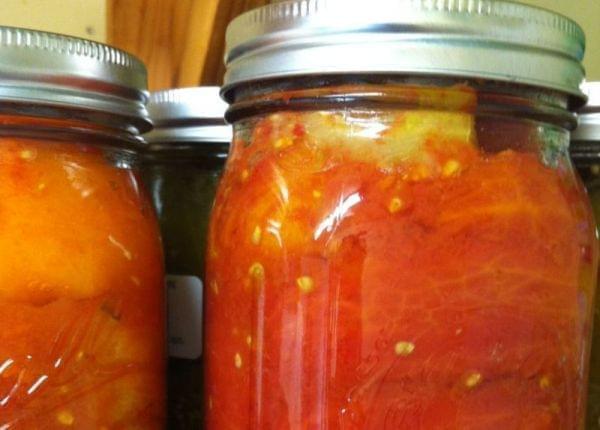 Jars of tomatoes on a shelf.