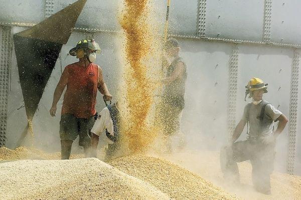 Workers drain corn from Haasbach LLC's Bin No. 9 as rescuers work inside to free three trapped boys July 28, 2010, in Mount Carroll, Ill. Triangular-shaped holes like the one pictured (left) were cut all around the bin to drain the corn evenly a