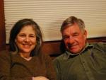 A middle-aged couple sitting together on a couch, smiling.
