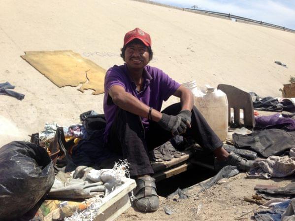 immigrant deported from Riverside, Calif. sits next the hole he lives in beneath Tijuana's fetid river canal.