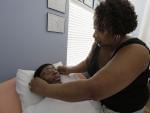 In this photo taken April 5, 2011, Annette Clark places glasses on her paralyzed son, Rocky Clark, in the bedroom at their home in Robbins, Ill. 