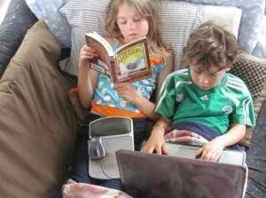 Girl reading and boy using laptop computer