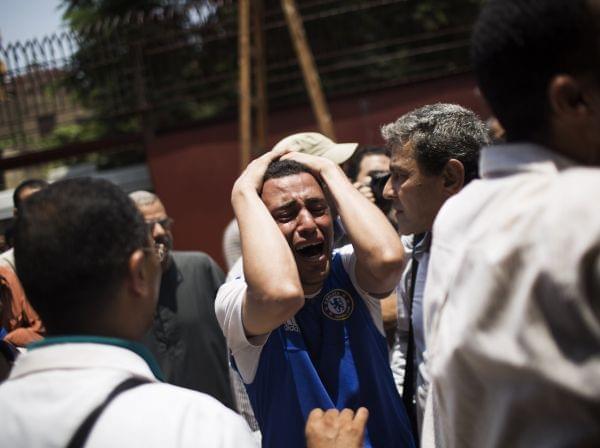 An Egyptian man cries outside a morgue after carrying the corpse of his brother killed near the Republican Guard building in Cairo