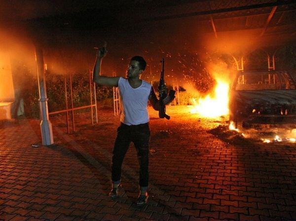 An armed man waves his rifle as buildings and cars are engulfed in flames after being set on fire inside the U.S. Consulate compound in Benghazi late on Sept. 11.