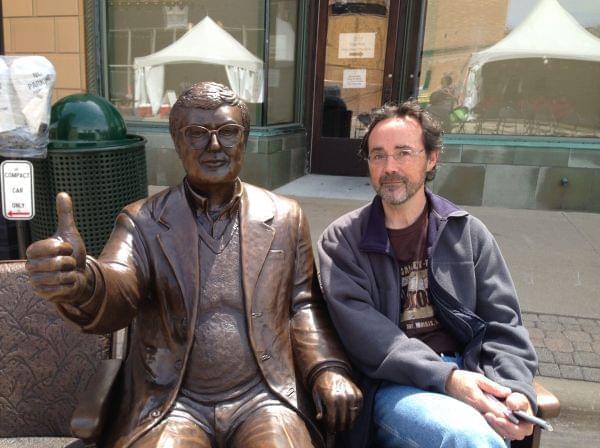 Artist Rick Harney poses next to his bronze sculpture of Roger Ebert on April 24, 2014 in Champaign, Ill.
