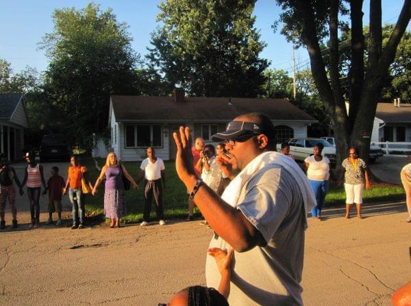 Rev. Lekevie Johnson of Jericho Missionary Baptist Church prays with about 100 participants gathered in a prayer circle during a community walk for peace in Champaign's Garden Hills neighborhood Wednesday evening.