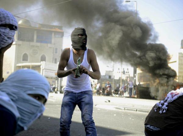 A Palestinian holds a Molotov cocktail during clashes with Israeli border police in Jerusalem on Wednesday, July 2, 2014.