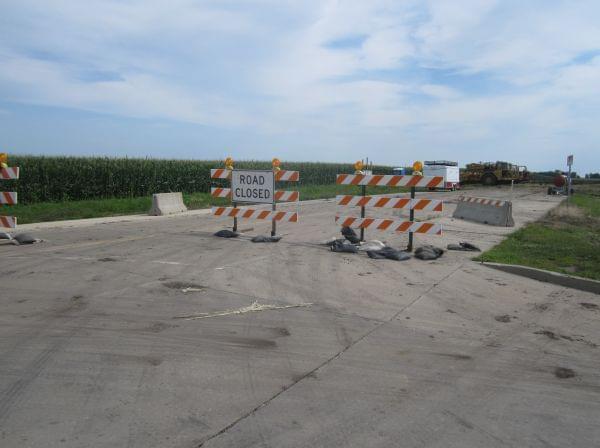 A "Road Closed" sign marks the east end of Olympian drive, where construction equipment is parked, awaiting work on the highway's extension.