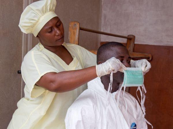 A healthcare worker, left, helps a collegue at Kenema Government Hospital.