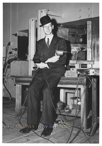 Donald W. Kerst, professor of physics at the University, poses in front of a Betatron particle accelerator wielding soldering gun and drill (ca. 1950).