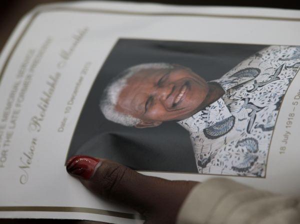 A woman holds the official programme during the memorial service for former South African president Nelson Mandela at the FNB Stadium in Soweto, near Johannesburg, South Africa, Tuesday Dec. 10, 2013. 