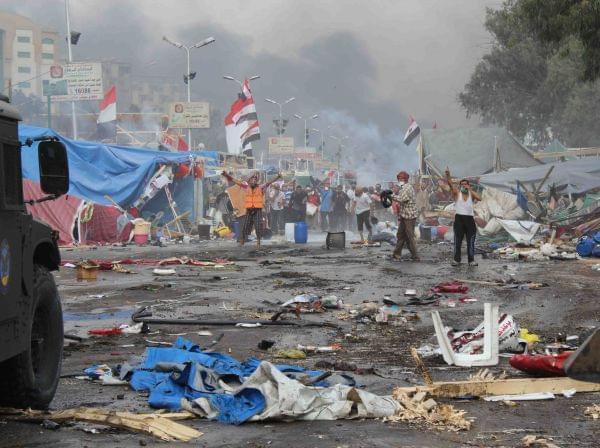 Supporters of ousted Islamist President Mohammed Morsi, stand among debris and smoke in background as they confront Egyptian security forces trying to clear the smaller of the two sit-ins, near the Cairo University campus in Giza, Cairo, Egypt, Wednesday, Aug. 14, 2013. Egyptian security forces, backed by armored cars and bulldozers, moved on Wednesday to clear two sit-in camps by supporters of the country's ousted President Mohammed Morsi, showering protesters with tear gas as the sound of gunfire rang out at both sites.