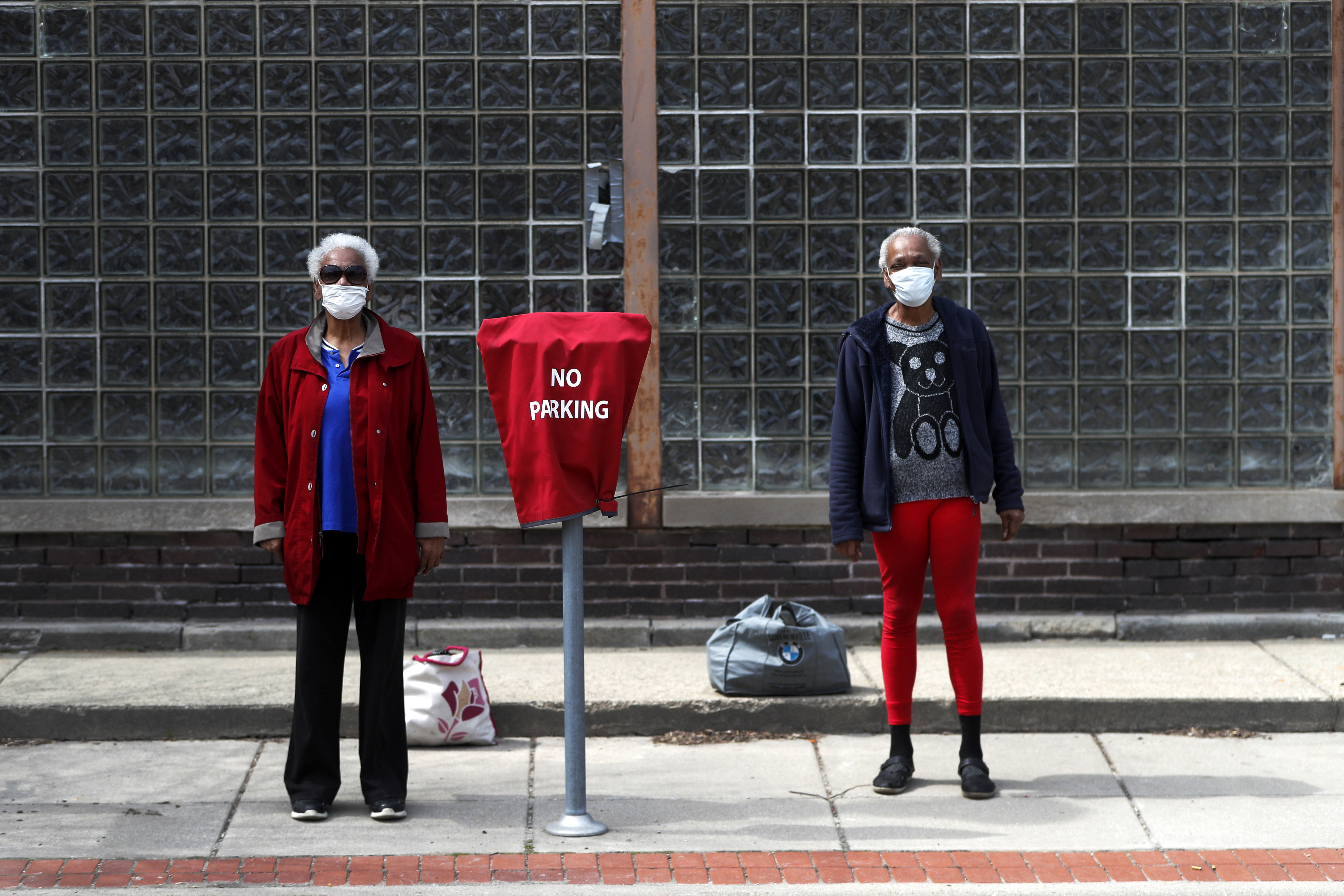 Sharon Hancock, left, and Shelia Theresa Adams pose for a portrait as they wait for the bus after visiting a friend in downtown Joliet, Ill., Monday, April 6, 2020. Chicago's mayor says the city is launching a health campaign focused on black and brown communities. Mayor Lori Lightfoot's comments Monday follow a WBEZ report highlighting the disproportionate number of black residents among those who have died of COVID-19 complications in the city.