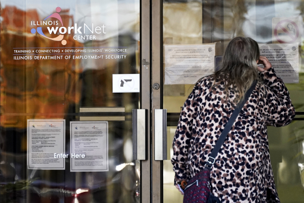 A woman checks information as information signs are displayed at IDES (Illinois Department of Employment Security) WorkNet center in Arlington Heights, Ill., Thursday, Nov. 5, 2020. Illinois reports biggest spike in unemployment claims of all states.