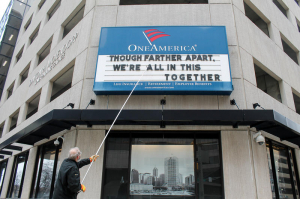 Un hombre ajusta el rótulo de One America en el centro de Indianapolis. Usualmente enseña una broma, pero el mensaje antes del mensaje de Gobernador dice: