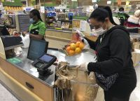 Yelitza Esteva, right, bags groceries for an order Wednesday, April 15, 2020, in Surfside, Fla. Esteva was a hairstylist. She now makes supermarket deliveries. Esteva and her husband work for the grocery delivery service Instacart and make an average of $150 per day, working more than 12 hours daily.
