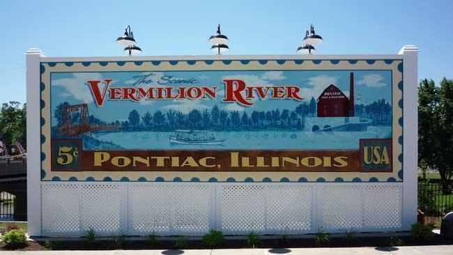 Painted sign in the shape of a postage stamp saying Vermilion River