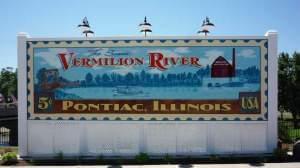 Painted sign in the shape of a postage stamp saying Vermilion River