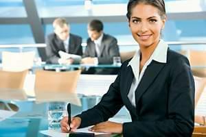 Woman in suit with pen smiling at meeting