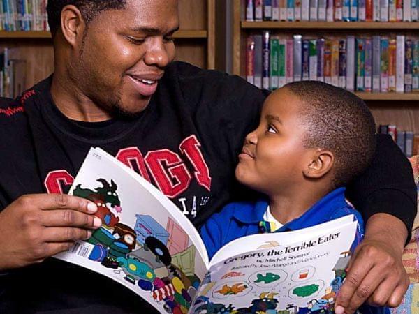 Adult book mentor reading to a very happy child
