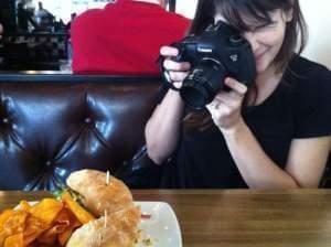 A young woman taking a photo of food at a restaurant.
