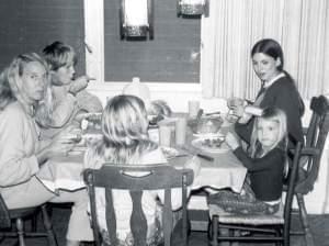 A young girl and several family members having dinner around the table.
