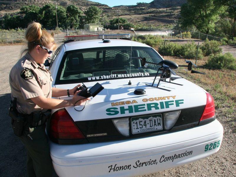 This undated photo provided by the Mesa County, Colo., Sheriff's Department, Deputy Amanda Hill of the Mesa County Sheriff’s Office in Colorado prepares to use a Draganflyer X6 drone equipped with a video camera to help search for a suspec