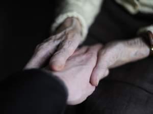 A woman suffering from Alzheimer's disease holds the hand of a relative in a retirement house in Angervilliers, France.