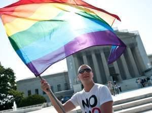 A gay rights activist waves a rainbow flag in front of the U.S. Supreme Court in June, a day before the ruling on the Defense of Marriage Act.