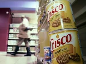 Crisco was the original product made with partially hydrogenated soybean oil, which contains trans fats. Today, Crisco has only small amounts of the fats.