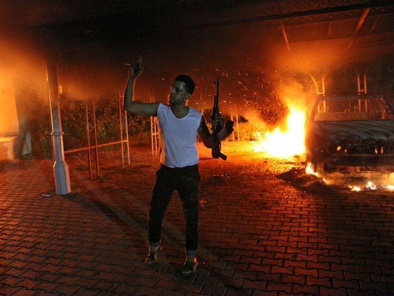 An armed man waves his rifle as buildings and cars are engulfed in flames after being set on fire inside the U.S. Consulate compound in Benghazi late on Sept. 11.