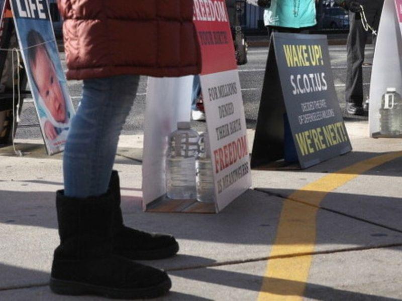 Anti-abortion protesters assemble outside the Planned Parenthood clinic in Boston on Dec. 7. The protesters are legally behind the 35-foot buffer zone, which is marked by a painted yellow line on the sidewalk.