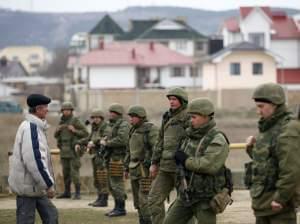 Ukrainian military personnel stand guard in the Crimean port city of Feodosia on Sunday. Ukraine is mobilizing for war, calling up reserve troops.