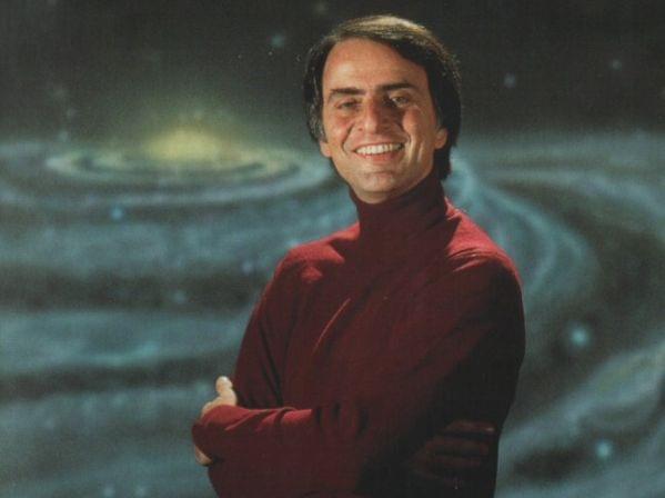 Carl Sagan standing in front of a spiral galaxy.