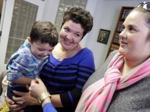 Nicole Yorksmith, left, holds her son while standing with her partner Pam Yorksmith. They were among four legally married couples who filed a federal civil rights lawsuit seeking to compel Ohio to recognize same-sex marriages on birth certificates.