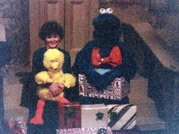 Paula Gray Havlik sits with David Thiel, who is dressed in a furry blue monster suit, on a replica of the Sesame Street steps.