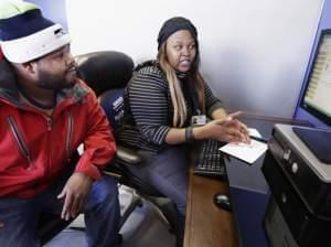 In this Nov. 8, 2013, photo, enrollment counselor Kenya Williams helps Jerome Davis Jr. 36, sign up for Medicaid at the Westside Health Authority in Chicago.