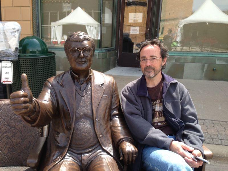 Artist Rick Harney poses next to his bronze sculpture of Roger Ebert on April 24, 2014 in Champaign, Ill.