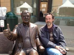 Artist Rick Harney poses next to his bronze sculpture of Roger Ebert on April 24, 2014 in Champaign, Ill.