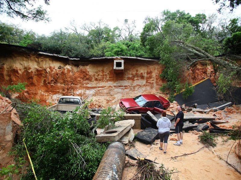 People survey the damage on Scenic Highway in Pensacola, Fla., after part of it collapsed following heavy rains and flash flooding on April 30.